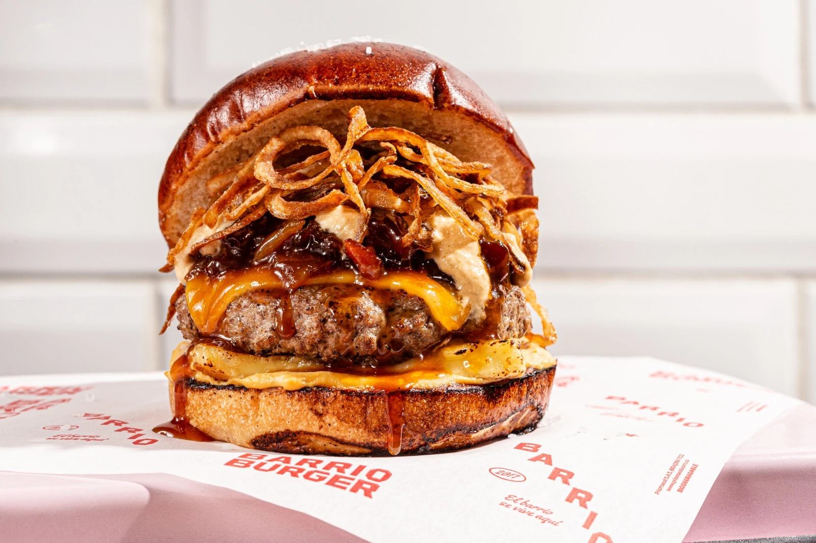 Provenza — hamburguesa brangus al carbón con queso costeño, cheddar, cebolla francesa crujiente y caramelo de bacon sobre pan pretzel.